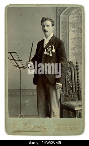 Viktorianische Carte de Visite (CDV) oder Visitenkarte eines jungen Dirigenten mit vielen Medaillen, aus dem Atelier von W. Crosby Molineux House, Abergele Road, Colwyn Bay, Anglesey, Wales, Großbritannien um 1890. Stockfoto