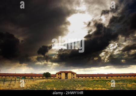 Altes Gebäude der Pferdefarm mit dunklen Wolken. Alte Bauernhausszene. Stockfoto