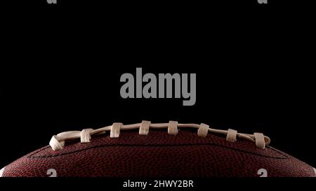 American Football and Sports Night Event-Konzept mit Nahaufnahme auf den Schnürsenkeln eines Lederballs isoliert auf schwarzem Hintergrund mit dramatischem Licht Stockfoto