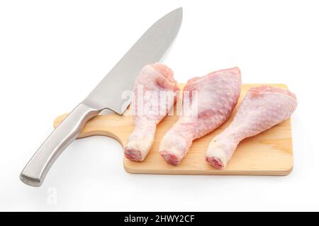 Lebensmittelzubereitung, eiweißreiche Lebensmittel und gesunde Zutaten Konzept mit rohen Hähnchenbeinen und Messer auf Holz Schneidebrett isoliert auf weißem Backgrou Stockfoto