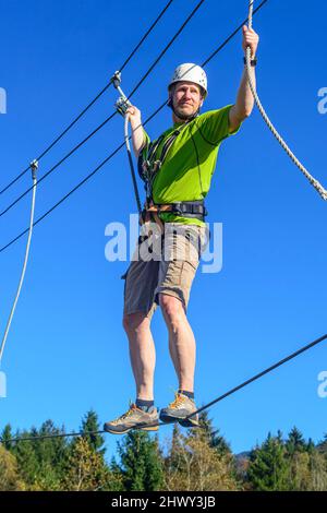 Man Balancieren auf hohem Seil im Hochseilgarten Stockfoto