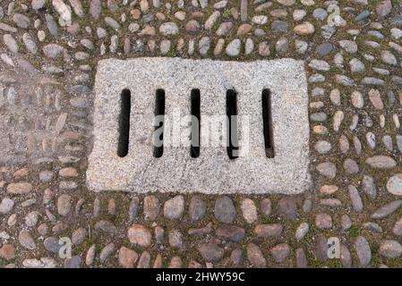 Antiker Steinwasserablauf in einer gepflasterten Straße, Blick von oben Stockfoto