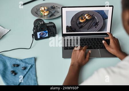 Nahaufnahme des Food-Fotografen, der Bilder mit einem Laptop im Studio bearbeitet, Kopierbereich Stockfoto