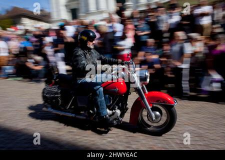 Ein Motorradfahrer kommt bei einer Parade in Solothurn, Schweiz, an einer jubelnden Menschenmenge vorbei. Stockfoto