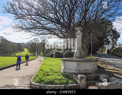 Brunnen in Cremyll auf dem Weg zu den Toren des Mount Edgcumbe House, auf dem Rame Peninusla in Cornwall. Spaziergänger, die sich für einen frühen Marsch gekleidet haben Stockfoto