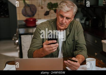 Kaukasischer älterer Mann betonte, dass Online-Zahlung Stockfoto
