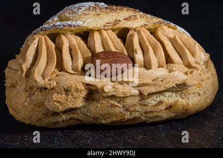 Fotografieren Sie auf einem schwarzen Hintergrund eines köstlichen Paris-Brest Stockfoto