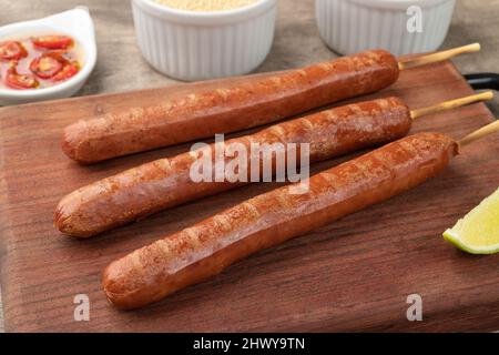 Schweinewurstspieße auf Holzbrett mit Farofa, Zitrone und Pfeffer. Stockfoto