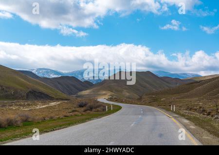 Kurvenreiche Asphaltstraße in einer bergigen Gegend Stockfoto