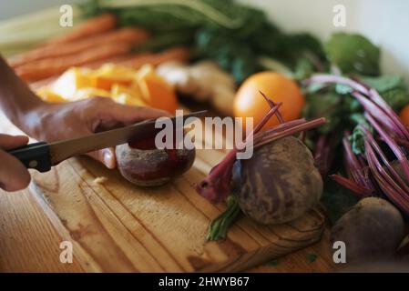 Dies ist die beste Rote Bete. Kurzer Schuss einer Frau, die Obst und Gemüse auf einem Schneidebrett schneiden soll. Stockfoto