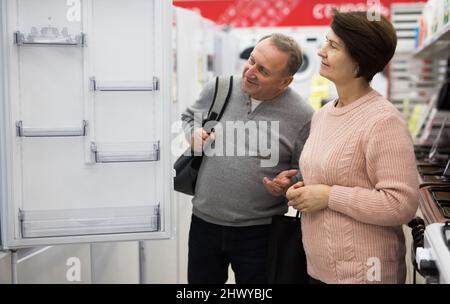 Meine Frau und mein Mann mittleren Alters pflücken im Laden einen neuen Kühlschrank Stockfoto