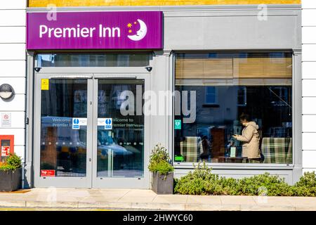 Epsom Surrey London, 8 2022. März, Eingang des modernen Premier Inn Hotels mit Kunden, der im Fenster steht Stockfoto