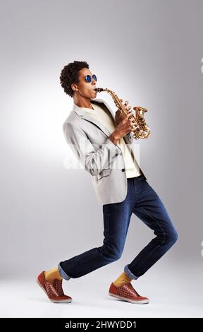 Jazz it up a Little. Studioaufnahme eines modischen jungen Mannes, der das Saxophon spielt. Stockfoto