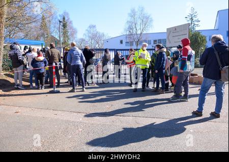 Hamburg, Deutschland. 08. März 2022. Flüchtlinge, Freiwillige und Polizisten stehen vor der Zentralen Erstaufnahmestelle (ZEA) in Rahlstedt. Die CDU im hamburger parlament hat dem Senat unhaltbare Bedingungen an der zentralen Ankunftsstelle für Flüchtlinge vorgeworfen. Quelle: Jonas Walzberg/dpa/Alamy Live News Stockfoto