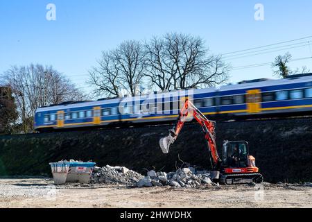 Oldenburg, Deutschland. 08. März 2022. Ein Zug fährt an der Baustelle der Strecke Oldenburg-Wilhelmshaven vorbei. Kritiker einer Güterzugstrecke durch Oldenburg sind mit einer Verfassungsbeschwerde in Karlsruhe gescheitert. Die Strecke zwischen Oldenburg und Wilhelmshaven wird ausgebaut, um die Verbindungen zum JadeWeserPort-Hafen zu verbessern. Die Stadt Oldenburg hätte eine Umgehungsstraße bevorzugt, um kilometerlange Lärmschutzwände zu vermeiden. Quelle: Sina Schuldt/dpa/Alamy Live News Stockfoto