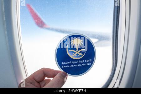 6. Dezember 2021, Jeddah, Saudi-Arabien. Das Emblem der Fluggesellschaft Saudi Arabian Airlines auf dem Hintergrund des Fensters des Flugzeugs. Stockfoto