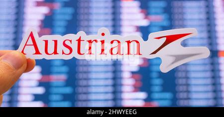 11. Dezember 2021, Wien, Österreich. Das Emblem der Austrian Airlines vor dem Hintergrund einer elektronischen Tafel mit Flugplänen auf der internationalen Flugbahn Stockfoto