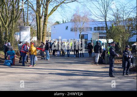 Hamburg, Deutschland. 08. März 2022. Flüchtlinge, Freiwillige und Polizisten stehen vor der Zentralen Erstaufnahmestelle (ZEA) in Rahlstedt. Die CDU im hamburger parlament hat dem Senat unhaltbare Bedingungen an der zentralen Ankunftsstelle für Flüchtlinge vorgeworfen. Quelle: Jonas Walzberg/dpa/Alamy Live News Stockfoto