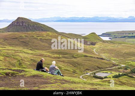 Ein Paar mittleren Alters genießt die Aussicht auf dem Quiraing Walk im Norden der Isle of Skye, Highland, Schottland, Großbritannien. Stockfoto