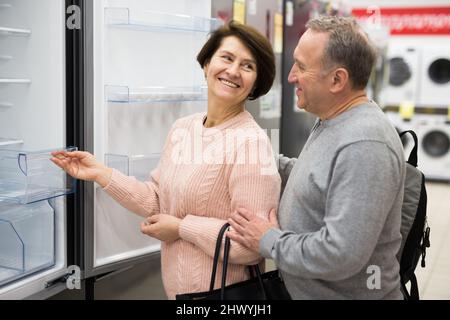 Meine Frau und mein Mann mittleren Alters pflücken im Laden einen neuen Kühlschrank Stockfoto