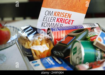 „Wenn der Krieg kommt“ Informationen und eine Schachtel mit Lebensmitteln und anderen Notwendigkeiten in einem Haus, das in einer Krise oder einem Krieg benötigt werden könnte. „Wenn der Krieg kommt“ (Schwedisch: OM kriget kommer) ist eine Broschüre, die ursprünglich vom Obersten Befehlshaber der schwedischen Streitkräfte erstellt wurde. Stockfoto