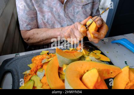 Alte Frau schneidet und Pillen gelben Kürbis, Kochen Kürbissuppe, Ruhestand Leben, selektive Konzentration Stockfoto