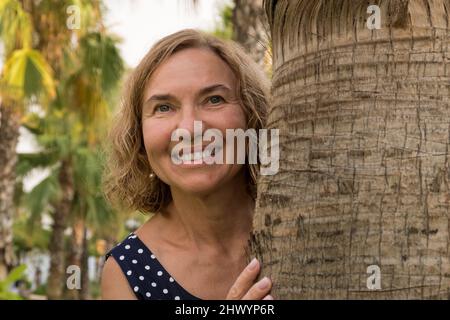 Porträt einer reifen Frau von 50-60 Jahren vor dem Hintergrund von Palmen Stockfoto