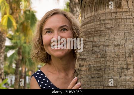 Porträt einer reifen Frau von 50-60 Jahren vor dem Hintergrund von Palmen Stockfoto