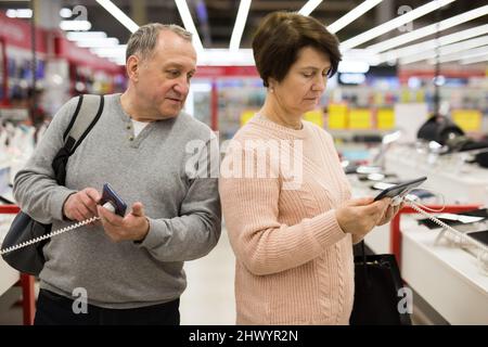 Europäische Ehegatten im reifen Alter wählen ein Tablet und ein Mobiltelefon Stockfoto