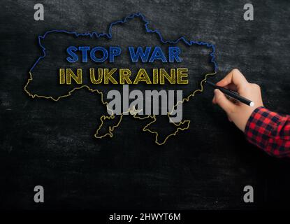 Girl zeichnet eine Karte der Ukraine mit dem Text Stop war in Ukraine auf der Tafel Stockfoto