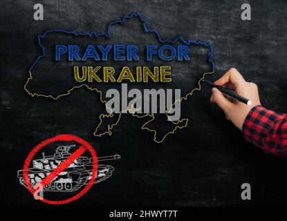 Girl zeichnet eine Landkarte der Ukraine mit dem Text Gebet für die Ukraine auf die Tafel Stockfoto