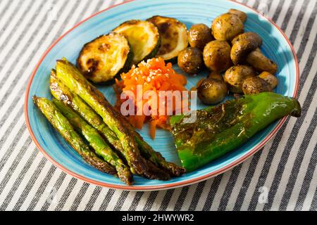 Auswahl an köstlichem gegrilltem Bio-Gemüse, serviert auf blauem Keramikteller. Stockfoto