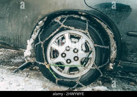 Autorad mit Schneeketten. Die Kotflügel des Autos werden durch den schlammigen Schnee vergessen. Das Konzept der Sicherheit auf verschneiten Straßen Stockfoto