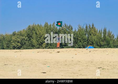 Die Flagge von Bangladesch wird von einem Mann geschwenkt, der Erfolg feiert. Eine schöne Aussicht auf die rote und grüne Flagge (die Nationalflagge von Bangladesch). Stockfoto