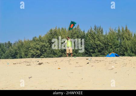 Die Flagge von Bangladesch wird von einem Mann geschwenkt, der Erfolg feiert. Eine schöne Aussicht auf die rote und grüne Flagge (die Nationalflagge von Bangladesch). Stockfoto