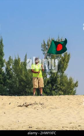 Die Flagge von Bangladesch wird von einem Mann geschwenkt, der Erfolg feiert. Eine schöne Aussicht auf die rote und grüne Flagge (die Nationalflagge von Bangladesch). Stockfoto