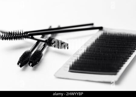 Setzen Sie schwarze Wimpern und Werkzeuge für Wimpern Verlängerung Verfahren auf weißen isolierten Hintergrund. Stockfoto