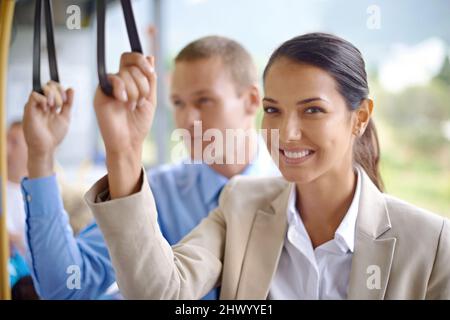 Mit dem Bus ist es besser. Zwei junge Kollegen, die im Bus unterwegs sind und sich an den Handschlaufen festhalten. Stockfoto