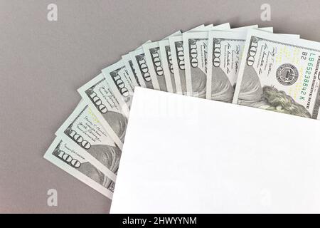 Teil eines weißen leeren Papierblatts mit amerikanischen 100-Dollar-Banknoten aus Papier auf grauem Hintergrund Stockfoto
