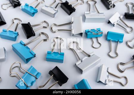 Fröhlicher Hintergrund von farbigen Büroklammern auf weißem Hintergrund. Büromaterial Stockfoto