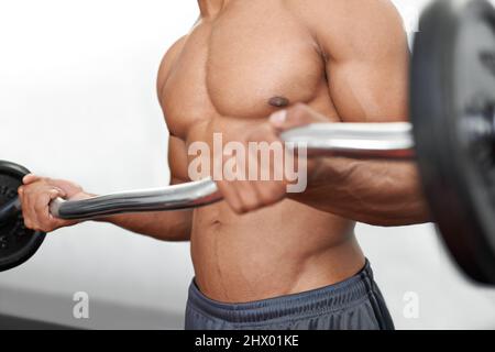 In Topform bleiben. Ein Mann, der Krafttraining in einer Turnhalle macht. Stockfoto