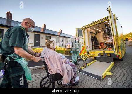 Sanitäter bringen einen Patienten in ihren Krankenwagen, nachdem er den Patienten in seinem Haus in der Nähe von Pontypool, S. Wales, Großbritannien, untersucht hat Stockfoto