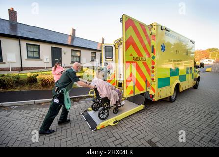 Sanitäter bringen einen Patienten in ihren Krankenwagen, nachdem er den Patienten in seinem Haus in der Nähe von Pontypool, S. Wales, Großbritannien, untersucht hat Stockfoto