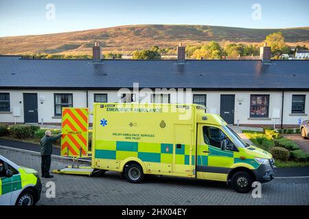 Sanitäter bringen einen Patienten in ihren Krankenwagen, nachdem er den Patienten in seinem Haus in der Nähe von Pontypool, S. Wales, Großbritannien, untersucht hat Stockfoto