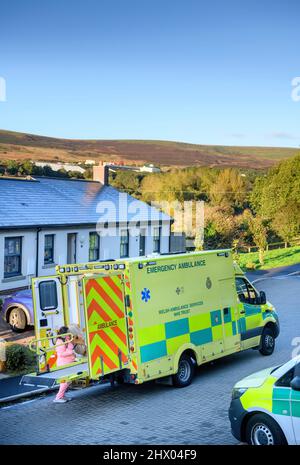 Sanitäter bringen einen Patienten in ihren Krankenwagen, nachdem er den Patienten in seinem Haus in der Nähe von Pontypool, S. Wales, Großbritannien, untersucht hat Stockfoto