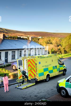 Sanitäter bringen einen Patienten in ihren Krankenwagen, nachdem er den Patienten in seinem Haus in der Nähe von Pontypool, S. Wales, Großbritannien, untersucht hat Stockfoto