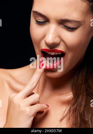 Zerreißendes Rot. Eine junge Frau mit roten Lippen und Nägeln. Stockfoto