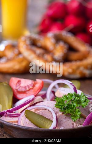 bayerischer Wurstsalat auf dunklem Holz Stockfoto