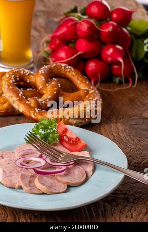 bayerischer Wurstsalat auf dunklem Holz Stockfoto