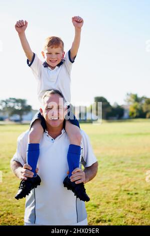 Papa ist der beste Trainer. Porträt eines Vaters, der seinen kleinen Sohn nach einem Fußballspiel auf den Schultern trägt. Stockfoto